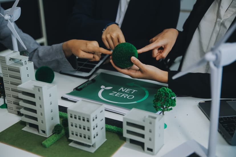 Hands collaborating over building models with NET ZERO sustainability concept