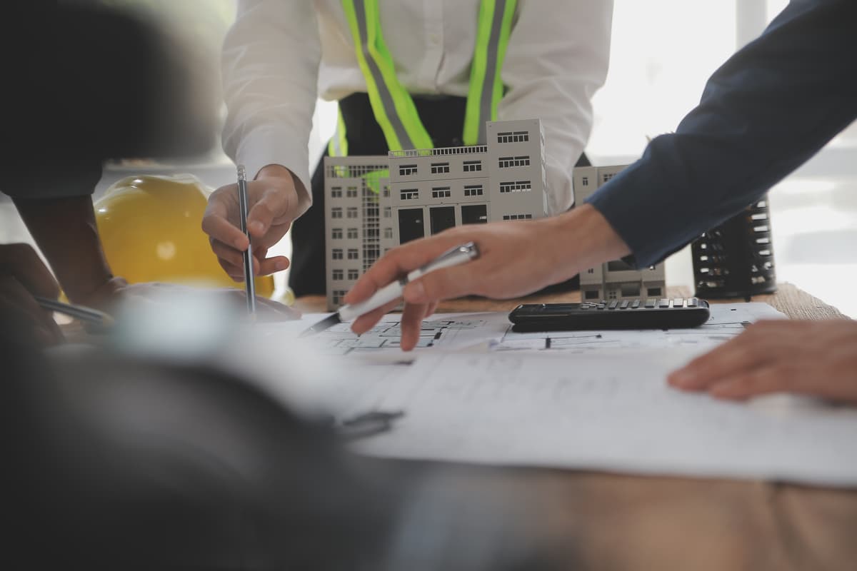 Construction professionals reviewing blueprints and building models during project planning meeting